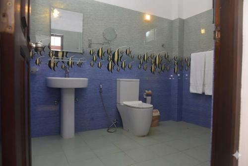 a blue bathroom with a toilet and a sink at The Lark Resort , Induruwa in Induruwa