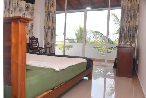 a bedroom with a bed and a large window at The Lark Resort , Induruwa in Induruwa