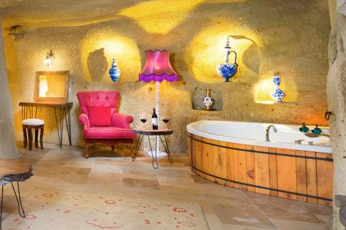 a bathroom with a tub and a chair and a table at Megaron Cave Hotel Cappadocia in Ortahisar