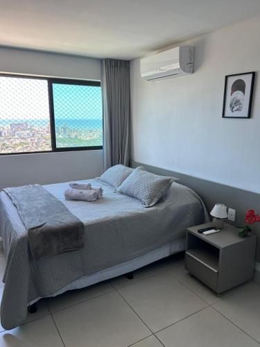a bedroom with a large bed and a window at Flat Ilha do Leite in Recife