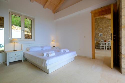 a white bedroom with a bed and a window at Erimitis View Villa in Magaziá