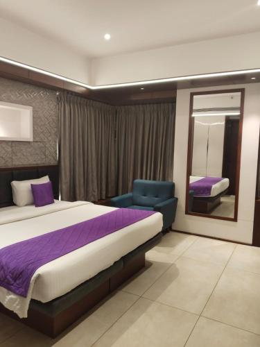 a bedroom with a bed and a chair and a mirror at SRS Suites in Bangalore