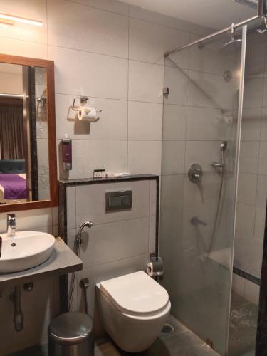 a bathroom with a shower and a toilet and a sink at SRS Suites in Bangalore