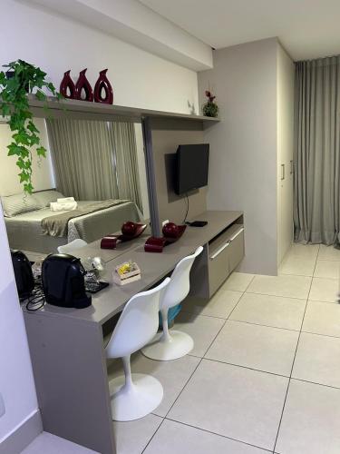 a room with a desk with two chairs and a television at Flat Ilha do Leite in Recife
