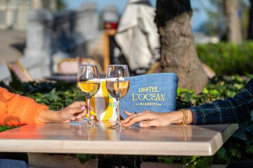 two people sitting at a table with glasses of wine at Hotel de l'Océan et restaurant - Coeur de ville in Biarritz