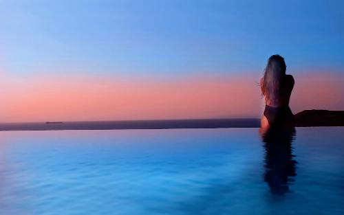 a woman standing in the water watching the sunset at Keablue in Melissaki