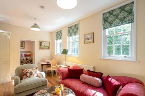 a living room with a red couch and some windows at Stable Yard Cottage in Osmaston