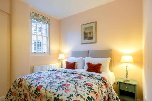 a bedroom with a bed and two lamps and a window at Stable Yard Cottage in Osmaston