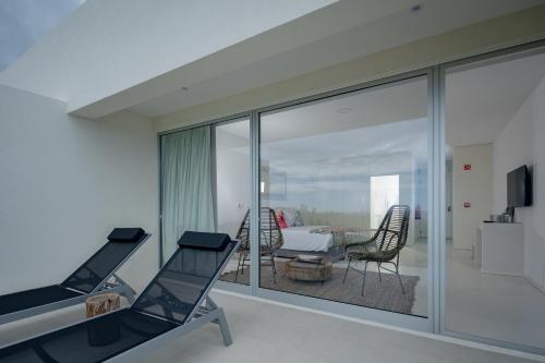 a living room with sliding glass doors and a table and chairs at Sul Villas & Spa - Azores in Lagoa