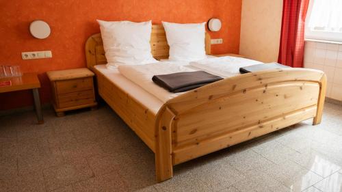 a bedroom with a wooden bed with white pillows at Hotel Eifeltor in Mechernich