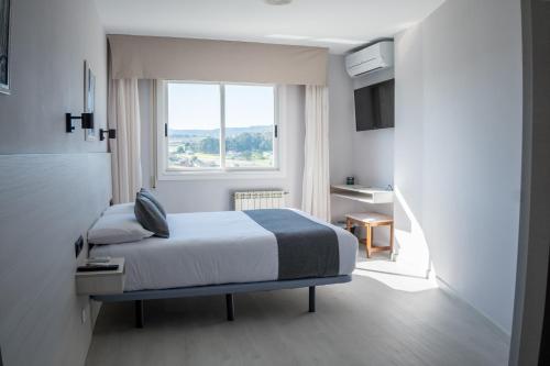 ein Hotelzimmer mit einem Bett und einem Fenster in der Unterkunft Alda Arteixo in Vilarrodis