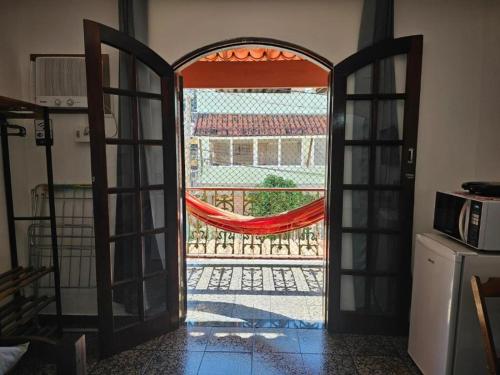 an open door to a patio with a hammock outside at Suíte Rodoviária no centro de Arraial in Arraial do Cabo