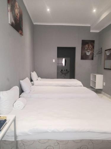 a bedroom with two large white beds in it at Red Hills Guesthouse in Tsumeb