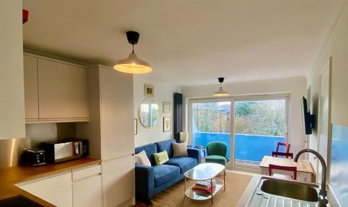 a kitchen and a living room with a blue couch at Modern 2-Bed Apartment with Off-Street Parking in Chiswick in London