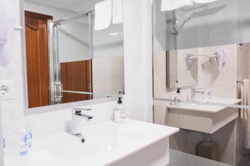 ein weißes Badezimmer mit zwei Waschbecken und einem Spiegel in der Unterkunft Alda Arteixo in Vilarrodis