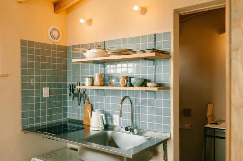 a kitchen with a sink and blue tiles at Ocean view cabin in Nanjo