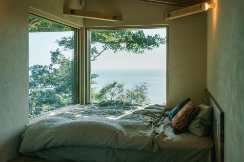 a bed in a room with a large window at Ocean view cabin in Nanjo