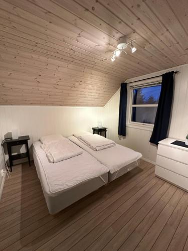 a bedroom with a large white bed and a window at Heggøy rorbuer in Heggøyni