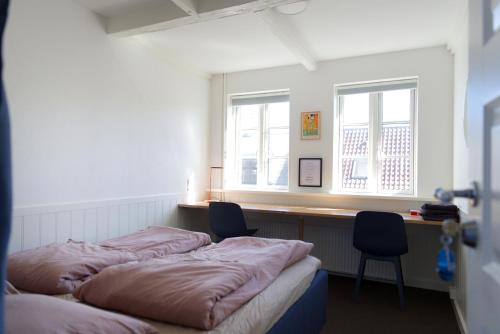 two beds in a room with two chairs and two windows at Gertruds Petit Hotel in Odense