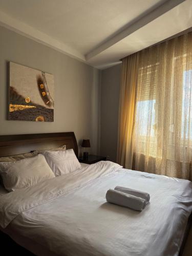 a white bed with a suitcase on top of it at Prishtina Center Apartment, 100m from Skanderbeg Square in Prishtinë
