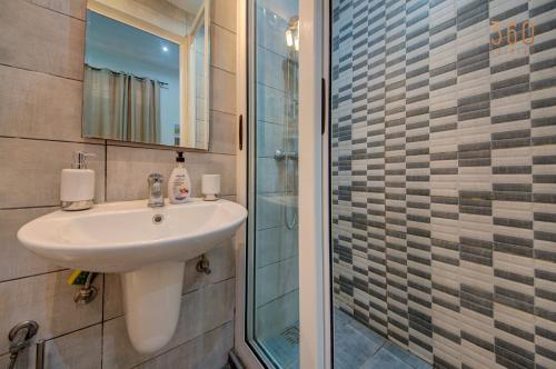 a bathroom with a sink and a glass shower at Suite Victory Authentic Maltese Duplex in Birgu in Birgu
