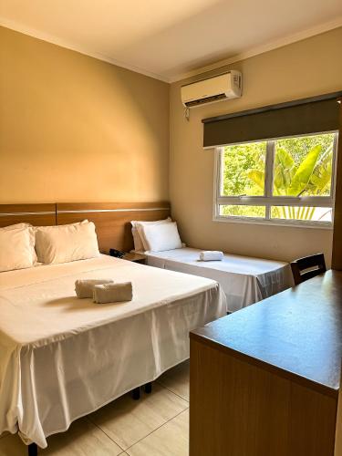 a room with two beds and a window at Hotel Stelati in Jaguariúna