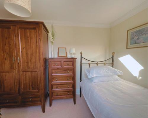 a bedroom with a bed with a wooden dresser and a wooden dresser at Buttercup Cottage in Killean