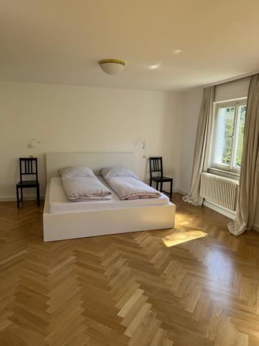 a white bed in a room with a wooden floor at Greenhouse in Fellbach