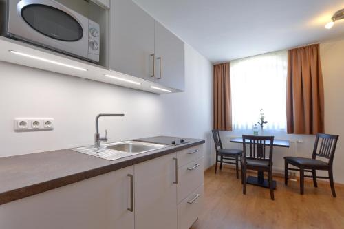 a kitchen with a sink and a table with chairs at Gästehaus am Lindenhain in Erding