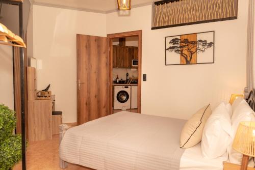 a bedroom with a white bed and a kitchen at F Tsimas apartment 1 in Skala Potamias