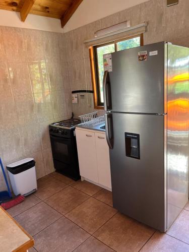 a kitchen with a stainless steel refrigerator and a stove at Cabañas arca 2 in Pucón