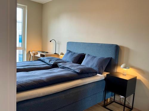 a bedroom with a bed with a blue headboard at Apartment by Kokstad tram in Bergen