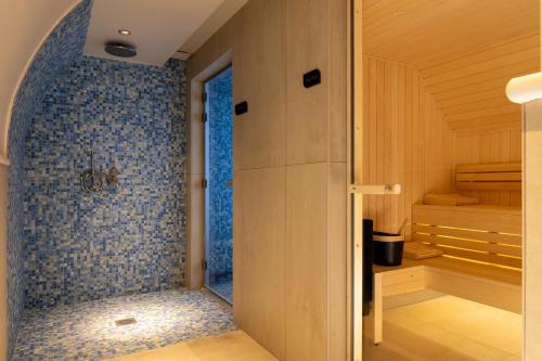 a bathroom with a shower with blue tiles on the wall at Hôtel le 6 Tiquetonne in Paris