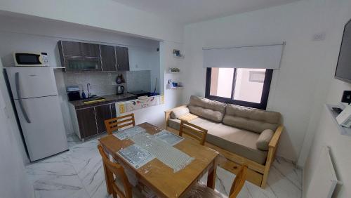 a kitchen and a living room with a table and a couch at Arena Studio Mar de Ajó in Mar de Ajó