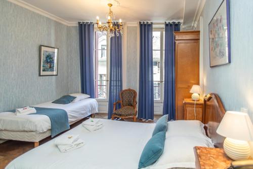 エヴィアン・レ・バンにあるHôtel Restaurant Continentalのベッドが2つとシャンデリアがあるホテルの部屋