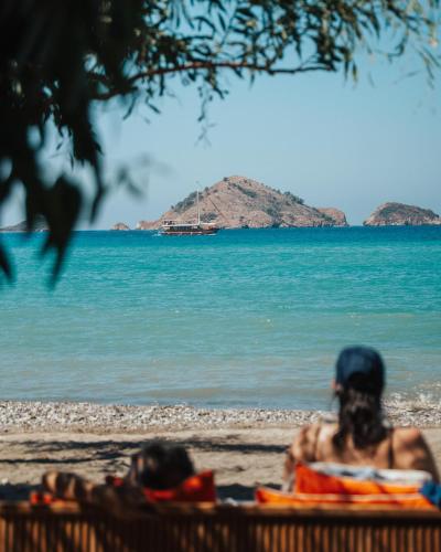 Zwei Personen sitzen am Strand und schauen aufs Wasser. in der Unterkunft Yonca Lodge in Fethiye