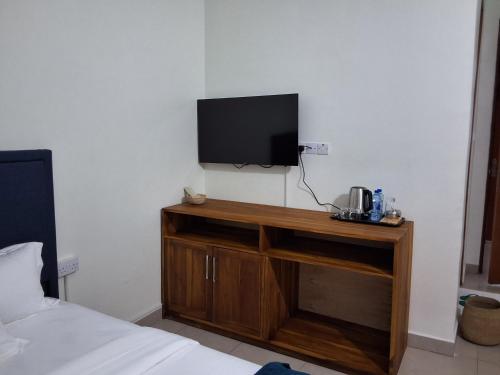 a bedroom with a television on a wooden cabinet at Yigs Motel in Iringa
