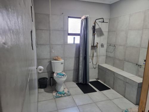 a bathroom with a toilet and a tub and a shower at Boskraai Self-Catering -74 Hornbill Street in St Lucia