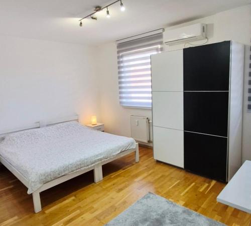 a bedroom with a bed and a large white refrigerator at Apartman IDEA in Zrenjanin