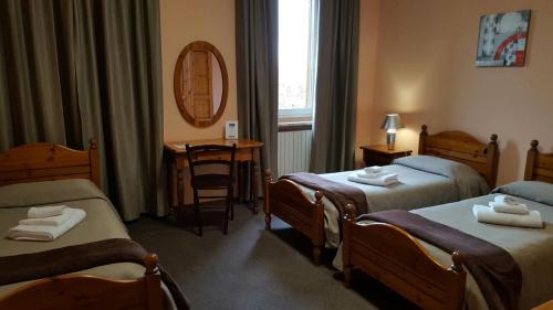 ビエッラにあるHotel Calalunaのベッド2台と鏡が備わるホテルルームです。