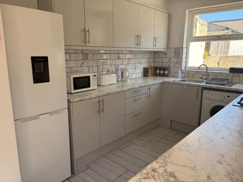a white kitchen with white cabinets and a microwave at Comfort at Sunderlands in Forest Hill