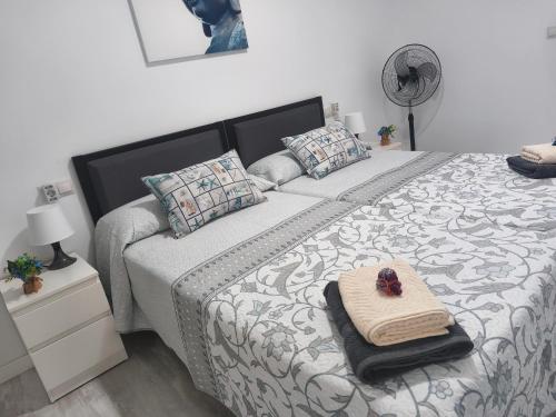 a bedroom with a bed with a towel and a fan at Apartamento Grao in Gandía