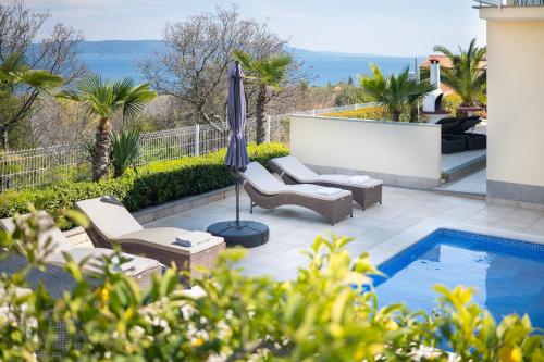 a patio with an umbrella and a swimming pool at Villa Bella Vista - apartments in Labin