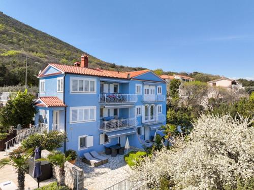 a large blue house with a hill in the background at Villa Bella Vista - apartments in Labin