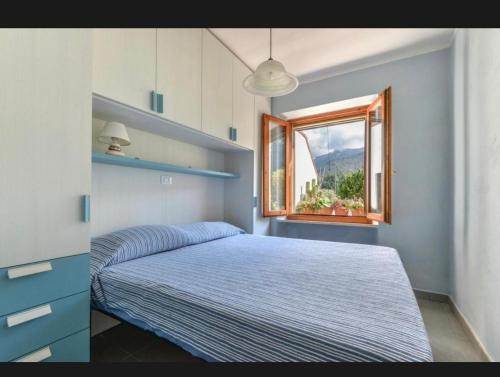 a bedroom with a blue bed and a window at Casa Gaia a soli 20 mt dal mare in Pomonte