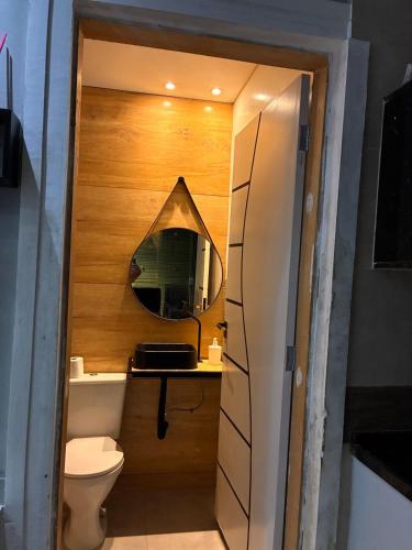 a bathroom with a toilet and a mirror at Onde o verão nunca termina! in Peruíbe