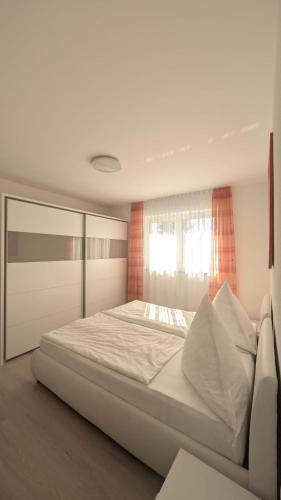 a bedroom with a large white bed with a window at Gemütliche Wohnung mit Terrasse nahe Würth in Künzelsau