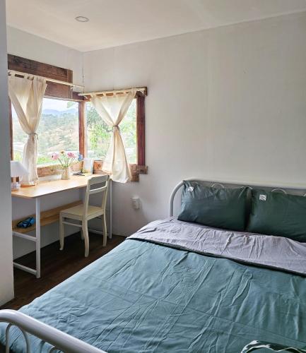 a bedroom with a bed and a desk and a window at Hiên nhà Đà Lạt in Ấp Kim Thạch