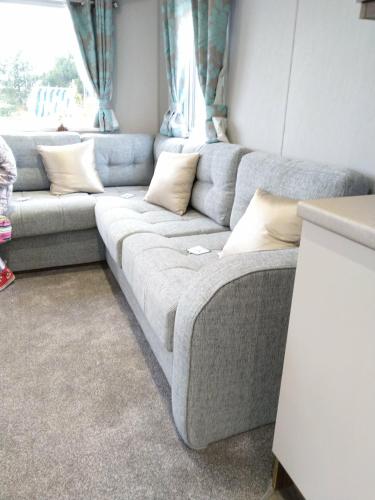 a gray couch in a room with a window at Nutmeg golden sands haven in Mablethorpe