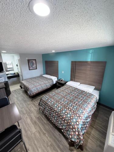 two beds in a hotel room with blue walls at Relax Inn Bryan College Station in Bryan